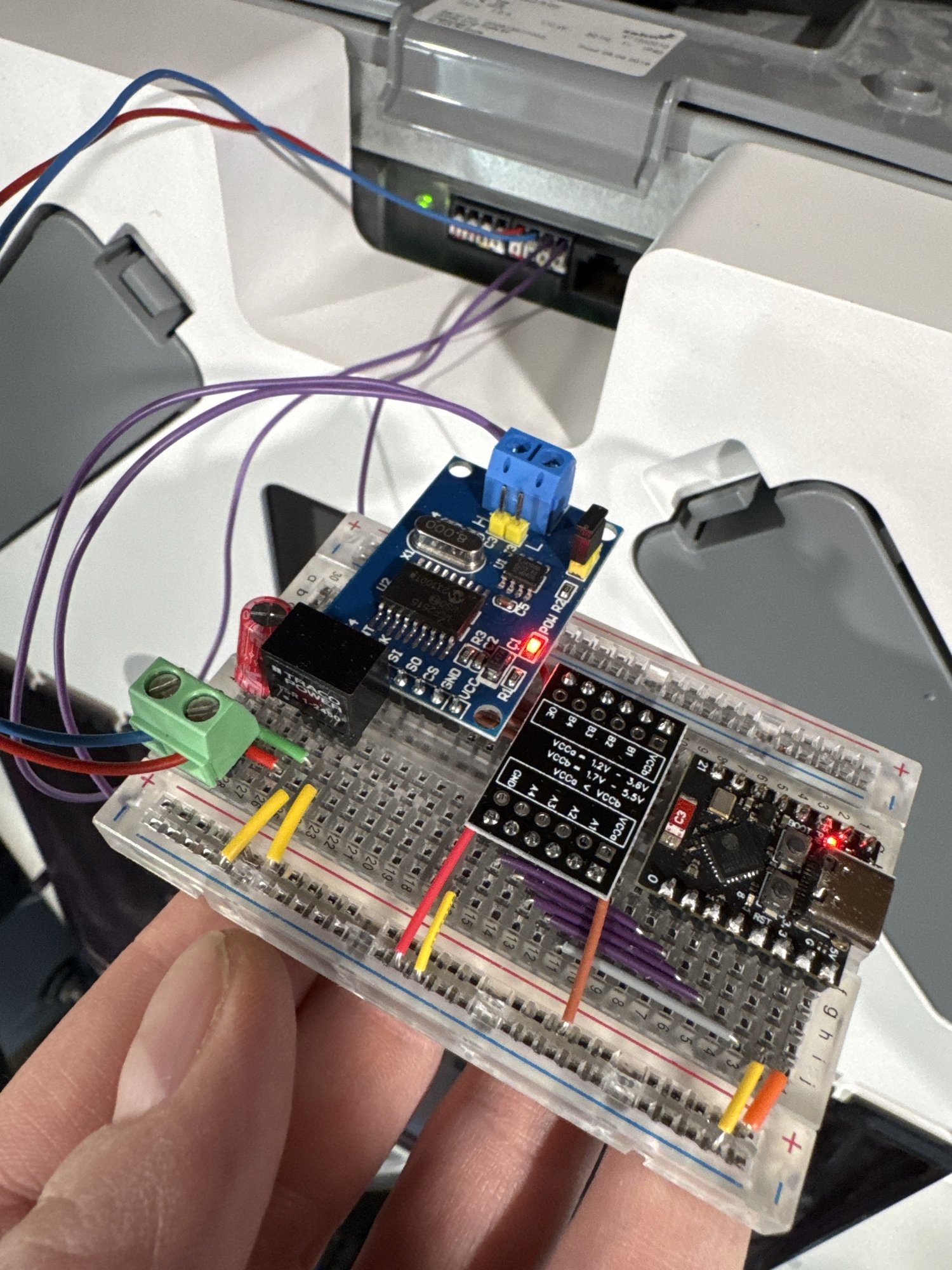 Breadboard with an ESP32-C3, MCP2515 CAN module, level shifter and voltage regulator, wired to the ComfoNet port of the ventilation unit